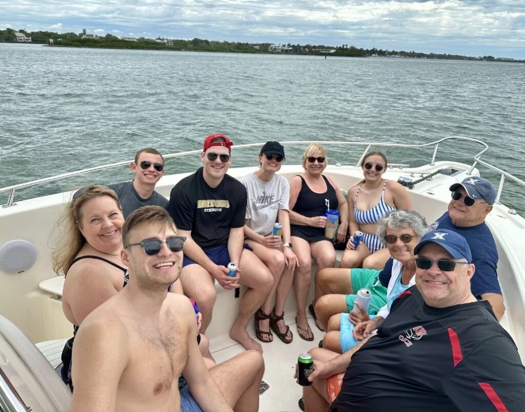 A group of nine adults sit together on a boat